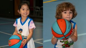 Two young children in a preschool basketball class holding a ball together, illustrating teamwork and social skill development at Little Boomers Basketball.