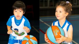 Professional basketball coach mentoring a 5-year-old boy during a Mini Boomers class, focusing on instructional listening skills and court confidence.
