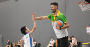 Coach celebrating a successful shot with a child during their first basketball class