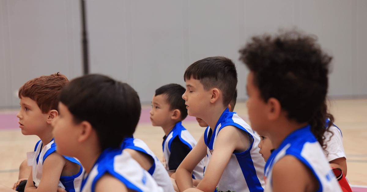 Young Mini Boomers (around 4 years old) listening attentively to their coach during a basketball session