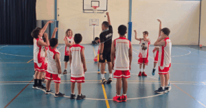 Children participating in a Little Boomers basketball session with their coach on the court