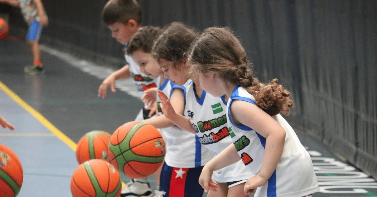 Young children learning how to dribble a basketball in a toddler class