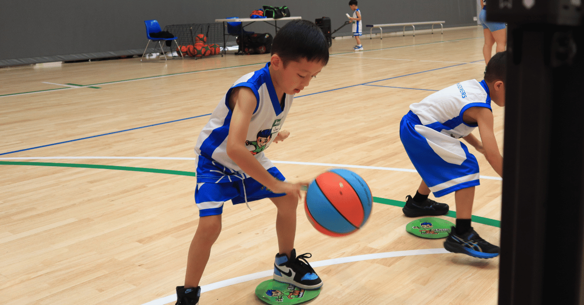 Young child practicing dribbling skills in a Little Boomers Basketball training session.