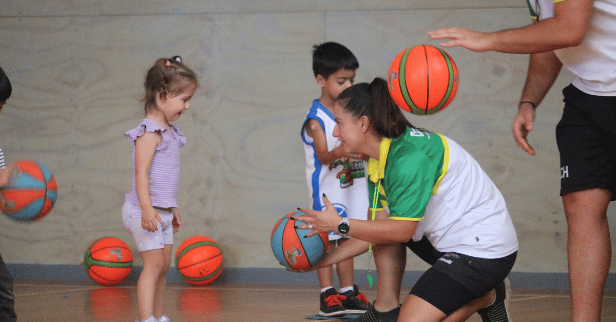 Coach helping a young girl learn basketball skills