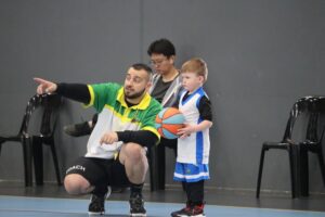 A man provides guidance to a young boy during a basketball game