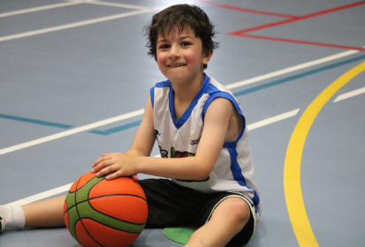 young boy sitting on basketball court